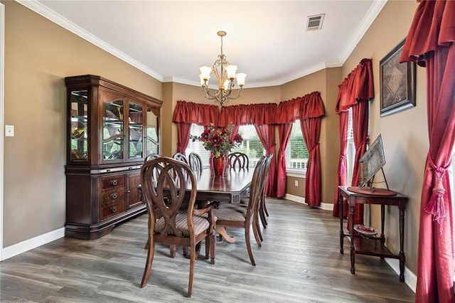 dining area featuring dark hardwood / wood-style flooring, ornamental molding, and an inviting chandelier