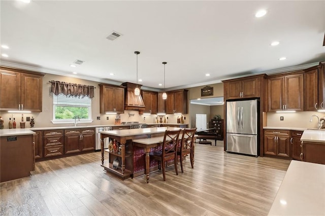 kitchen with sink, crown molding, hanging light fixtures, hardwood / wood-style flooring, and appliances with stainless steel finishes