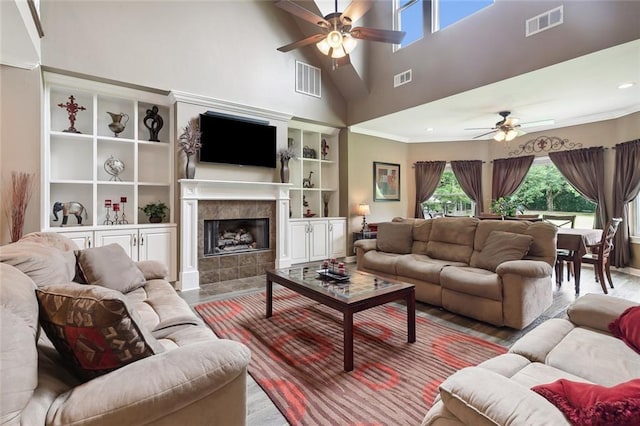 living room featuring a tile fireplace, ceiling fan, and built in features