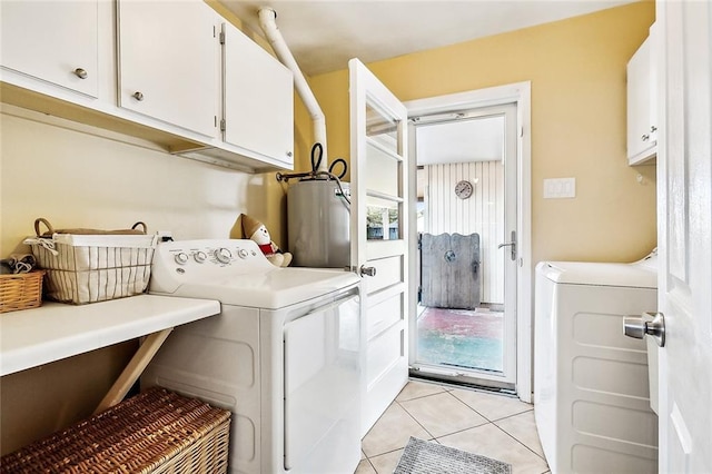 laundry area with light tile patterned flooring, cabinets, independent washer and dryer, and water heater