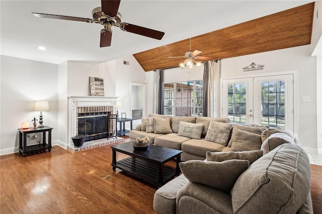 living room with a wealth of natural light, french doors, lofted ceiling, and a brick fireplace