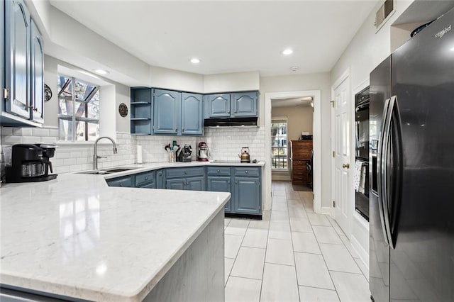 kitchen featuring blue cabinetry, sink, stainless steel refrigerator with ice dispenser, kitchen peninsula, and decorative backsplash