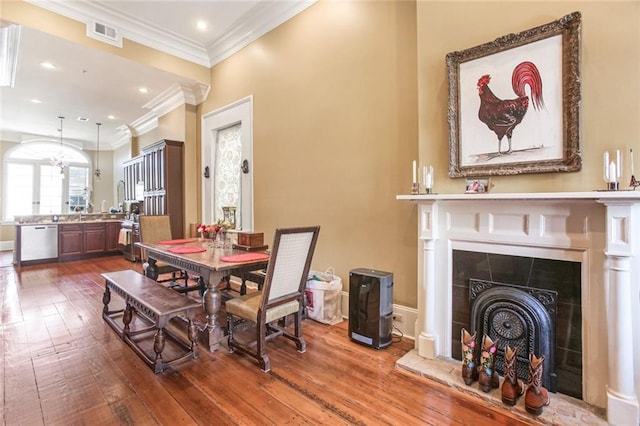 dining room featuring crown molding, a fireplace, and wood-type flooring