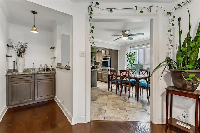 dining space with ceiling fan, sink, wood-type flooring, and ornamental molding