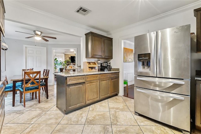 kitchen with stainless steel fridge, light stone counters, ceiling fan, and ornamental molding