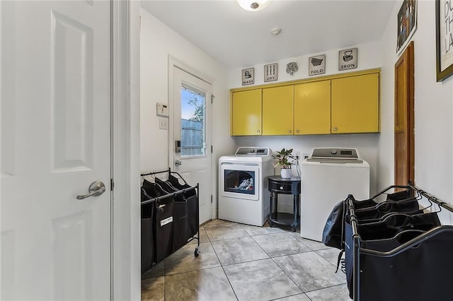 clothes washing area featuring separate washer and dryer, light tile patterned floors, and cabinets