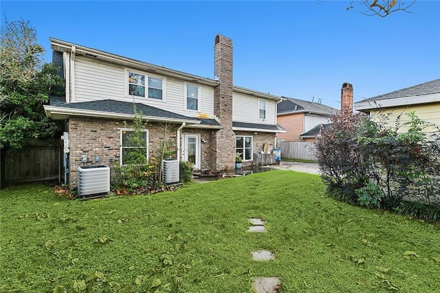 back of house with central AC unit and a lawn