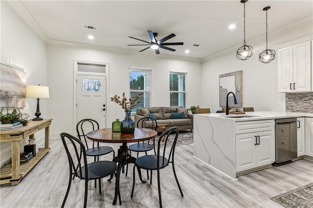 dining room featuring ceiling fan, ornamental molding, sink, and light wood-type flooring