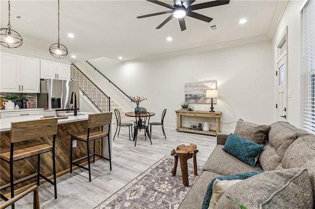 living room with crown molding, sink, ceiling fan, and light hardwood / wood-style floors