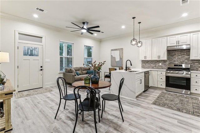 kitchen with appliances with stainless steel finishes, decorative light fixtures, white cabinetry, sink, and decorative backsplash