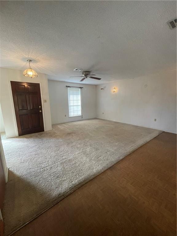 spare room featuring a textured ceiling and ceiling fan with notable chandelier