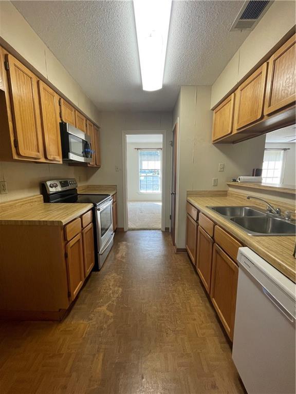 kitchen featuring a textured ceiling, a healthy amount of sunlight, sink, and appliances with stainless steel finishes