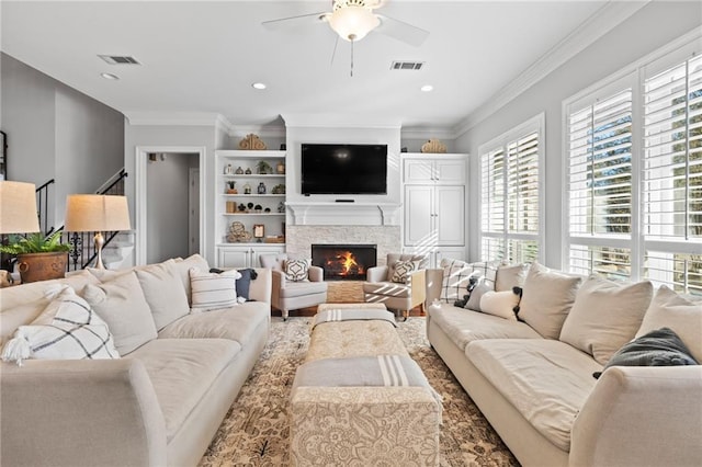 living room with a fireplace, ceiling fan, and ornamental molding