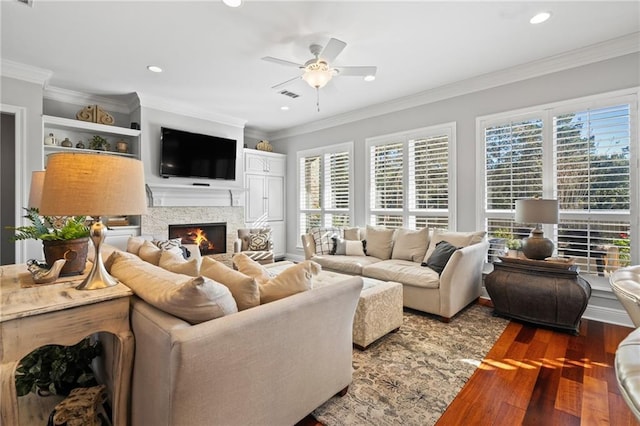 living room with a fireplace, crown molding, ceiling fan, and dark wood-type flooring