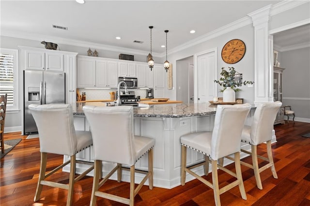 kitchen with a breakfast bar, appliances with stainless steel finishes, and a kitchen island with sink