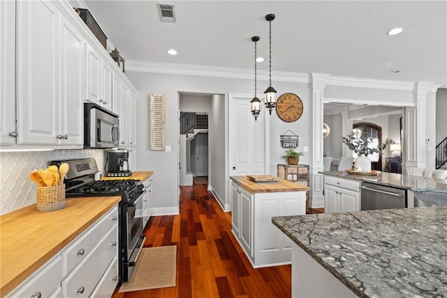 kitchen with wood counters, a center island, white cabinets, ornamental molding, and appliances with stainless steel finishes