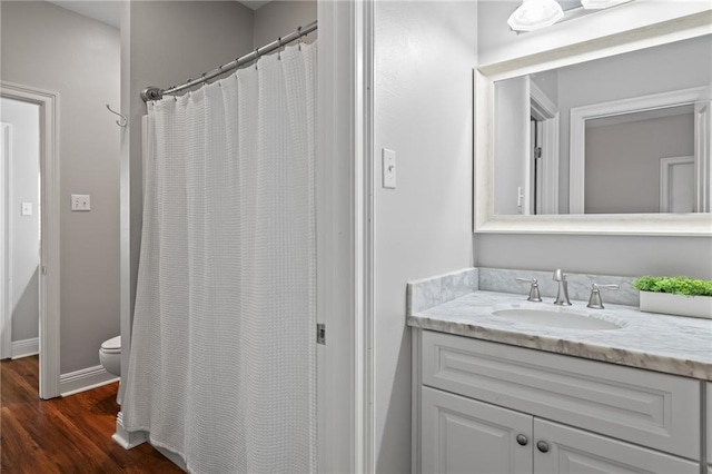 bathroom with curtained shower, vanity, wood-type flooring, and toilet