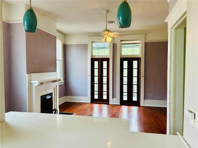 foyer entrance featuring ceiling fan, french doors, dark wood-type flooring, and a textured ceiling