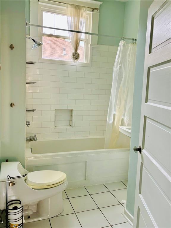 bathroom with tile patterned flooring, shower / tub combo with curtain, and toilet