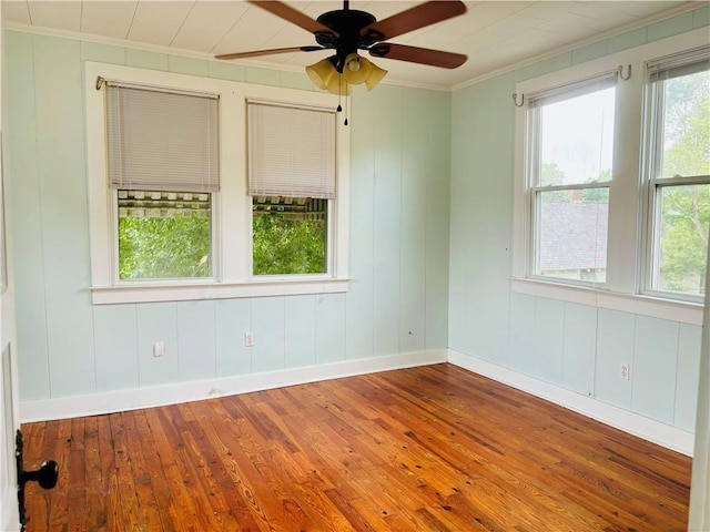 empty room featuring wood-type flooring, ceiling fan, and ornamental molding