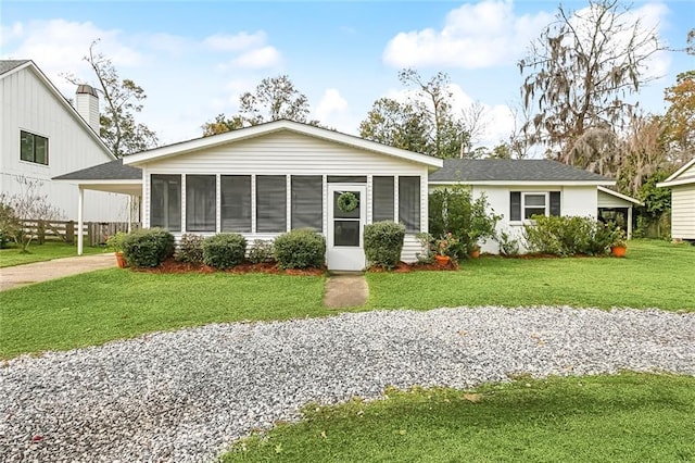 view of front of house with a front lawn, a carport, and a sunroom