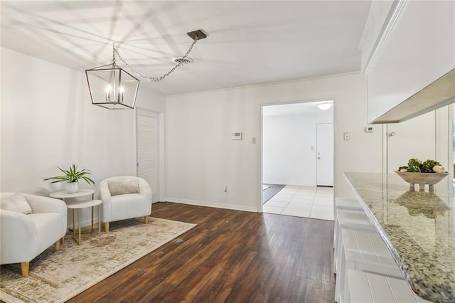 living area featuring crown molding, hardwood / wood-style flooring, and an inviting chandelier