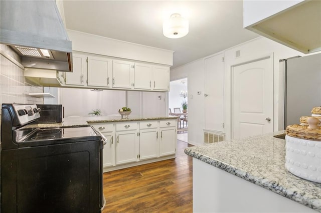 kitchen with dark wood-type flooring, stove, range hood, light stone countertops, and white cabinets