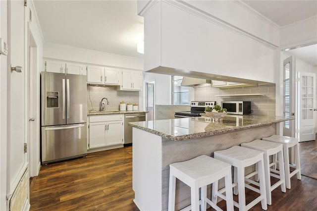 kitchen featuring crown molding, dark wood-type flooring, stone counters, white cabinetry, and stainless steel appliances