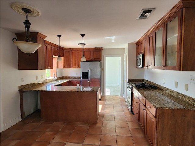 kitchen with tile patterned floors, stainless steel appliances, sink, dark stone countertops, and hanging light fixtures