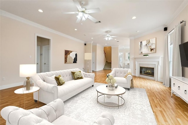 living room featuring ceiling fan, light wood-type flooring, and ornamental molding