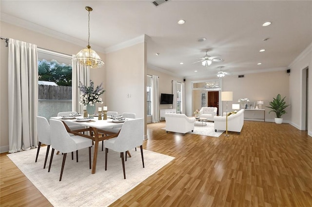 dining space with ceiling fan with notable chandelier, light hardwood / wood-style floors, and crown molding