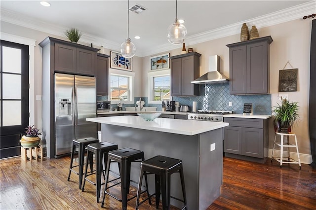 kitchen featuring pendant lighting, a breakfast bar, a kitchen island, stainless steel fridge with ice dispenser, and wall chimney exhaust hood