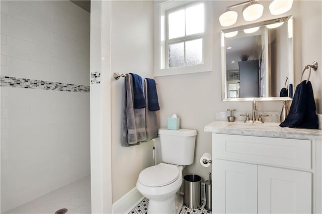 bathroom with vanity, tiled shower, and toilet