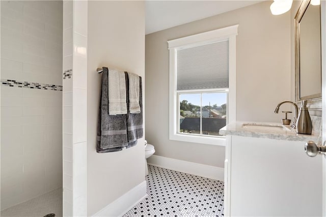 bathroom featuring vanity, a tile shower, and toilet