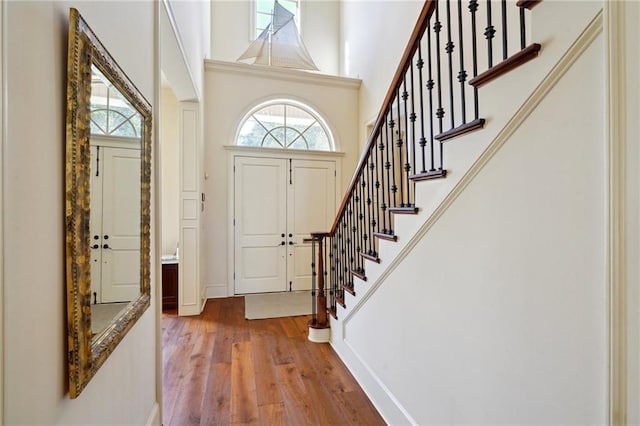 entrance foyer with a towering ceiling, light hardwood / wood-style floors, and a healthy amount of sunlight