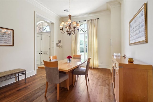 dining area featuring dark hardwood / wood-style flooring, ornamental molding, and an inviting chandelier