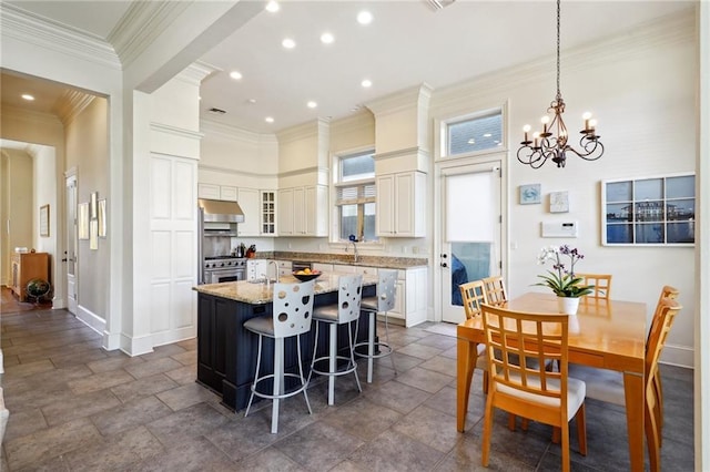 kitchen with pendant lighting, a center island, a kitchen breakfast bar, light stone countertops, and a notable chandelier