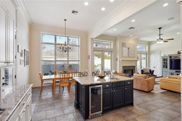 kitchen featuring plenty of natural light, light stone counters, beverage cooler, a kitchen island, and hanging light fixtures