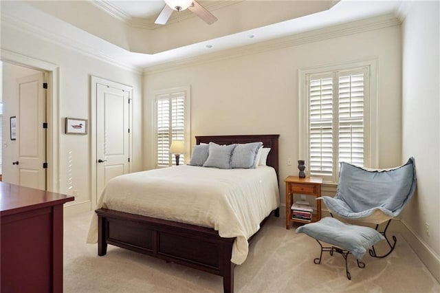 bedroom featuring a raised ceiling, multiple windows, ceiling fan, and light carpet