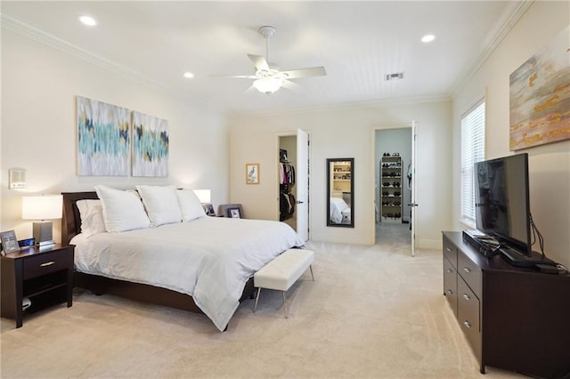 carpeted bedroom with a closet, a walk in closet, ceiling fan, and crown molding