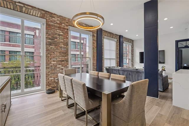 dining room featuring plenty of natural light, brick wall, and light wood-type flooring