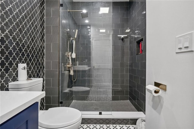 bathroom featuring toilet, vanity, tile patterned flooring, and tiled shower