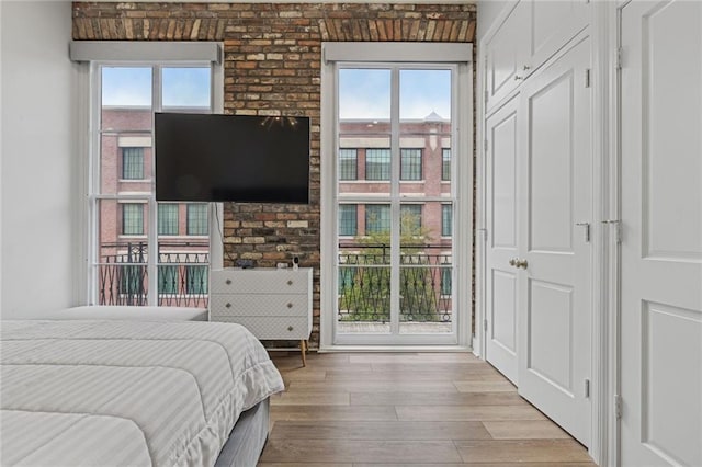 bedroom featuring brick wall and light wood-type flooring