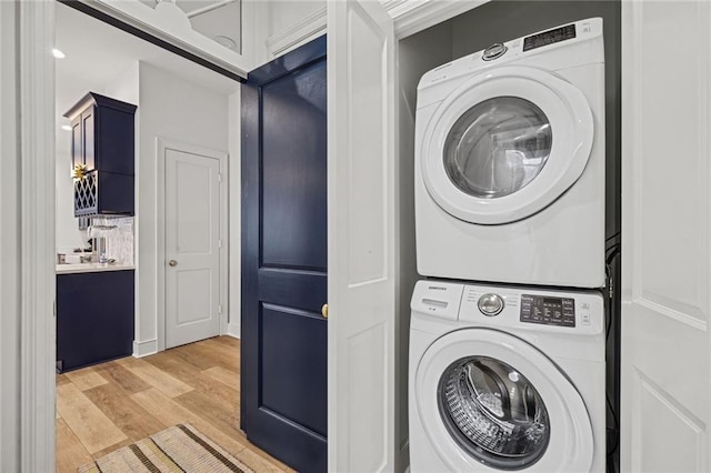 laundry area with stacked washer and dryer and light hardwood / wood-style floors