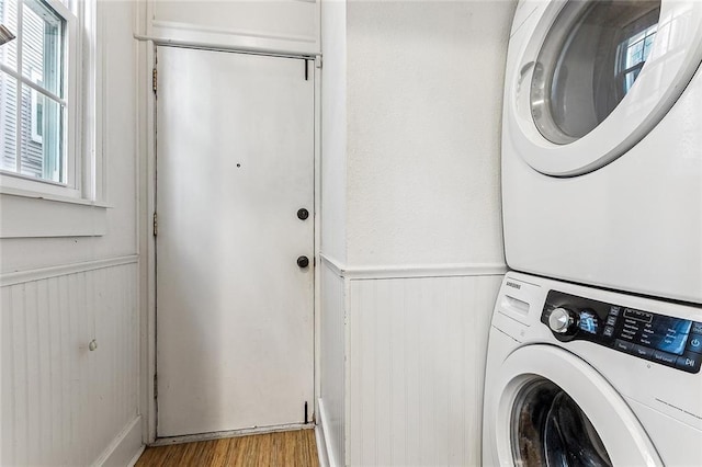 laundry room with stacked washing maching and dryer and light hardwood / wood-style floors