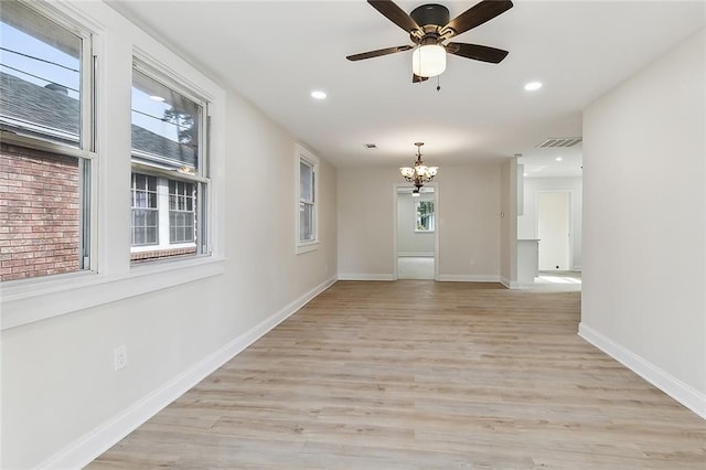 unfurnished room featuring ceiling fan with notable chandelier and light hardwood / wood-style flooring