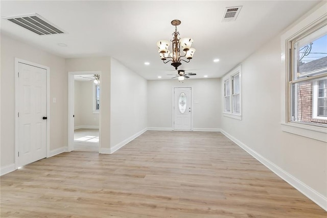 entrance foyer with a healthy amount of sunlight, ceiling fan with notable chandelier, and light hardwood / wood-style floors