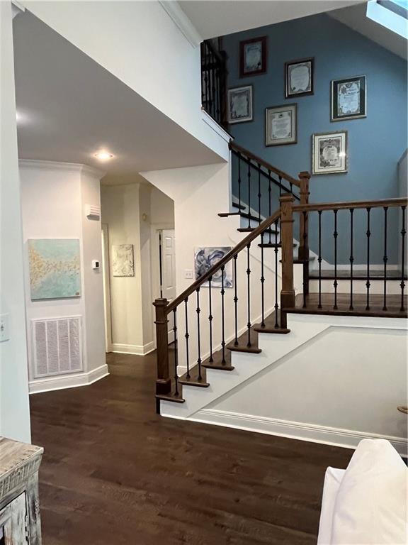 stairway with wood-type flooring, crown molding, and a skylight