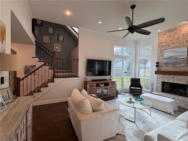 living room featuring ceiling fan, a fireplace, crown molding, and dark wood-type flooring