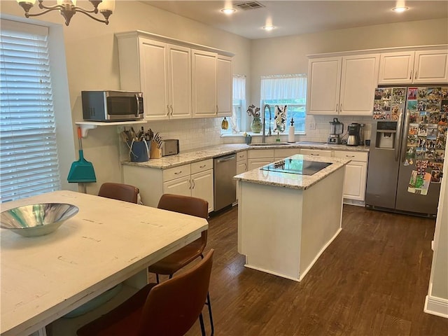 kitchen featuring white cabinetry, sink, a center island, light stone counters, and appliances with stainless steel finishes